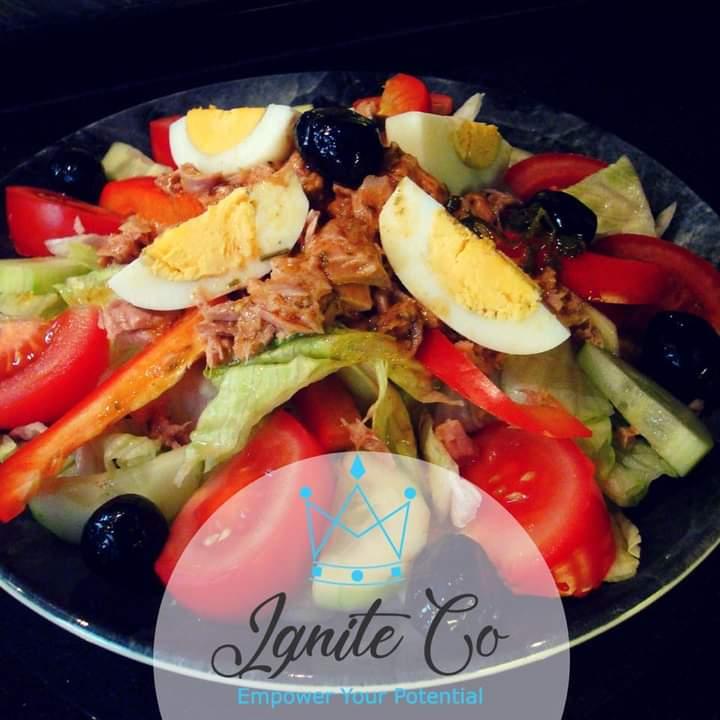 Plate with sliced tomatoes, lettuce, cucumbers, olives, boiled eggs, red peppers and tuna for nutrition from Ignite Co